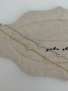 Close-up of gold and silver S925 four-leaf clover bracelets with zircon on linen bag