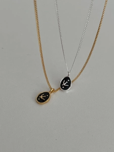 Detail shot of round swallow pendant necklaces with black enamel and starry bird design
