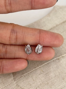 Close-up of S925 silver tulip earrings with sparkling zircon inlay held between fingers