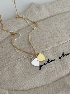 Detail shot of heart-shaped gold and silver necklaces on a textured linen pouch