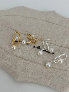 Detailed shot of gold and silver twisted hoop earrings with elegant white pearls