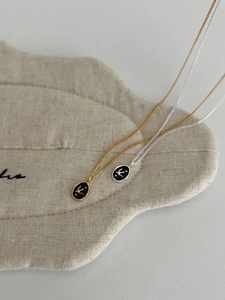 Detailed view of silver and gold swallow pendants with black enamel on beige fabric