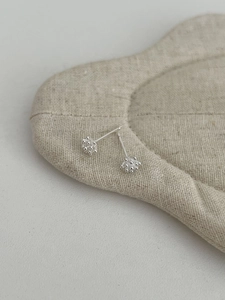 Macro shot of S925 sterling silver pine cone earrings on minimalist linen fabric