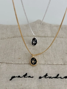 Detail of S925 silver oval swallow pendants in gold and silver finish on linen