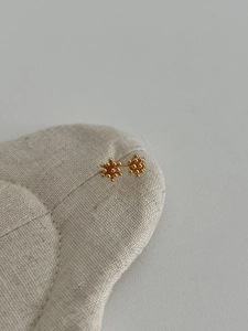 Macro shot of S925 silver pinecone stud earrings with golden textured finish