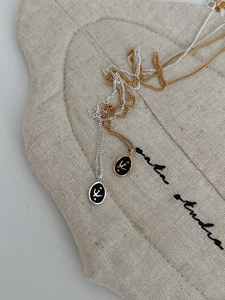 Detail showing gold and silver swallow pendants with black enamel on linen texture
