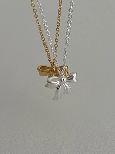 Close-up of elegant gold and silver bow pendant necklaces with fine cross chains