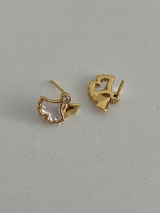 Close-up of golden ginkgo leaf earrings with white mother of pearl inlay and crystal