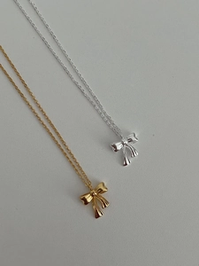 Macro view showing polished gold and silver bow pendants with delicate metal chains
