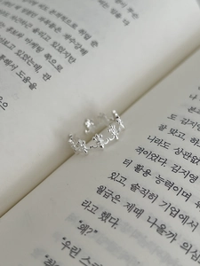 Detailed view of adjustable S925 silver vintage ring with iris petal patterns on a book