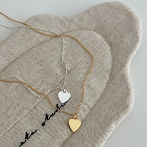 Minimalist S925 sterling silver heart necklaces in gold and silver finish on soft fabric