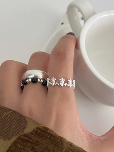 Macro detail of S925 silver stacked rings including a hollow floral cross pattern band