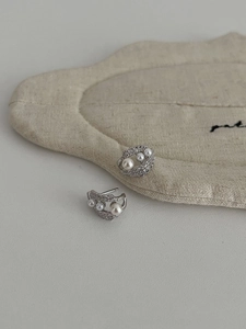 Detailed view of silver lace-style earrings with pave-set zircons and elegant white pearls