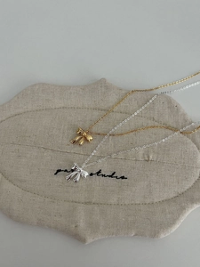 Close-up of bow knot pendants in gold and silver finishes on textured linen