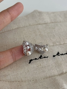 Macro shot of silver lace pearl earrings with shimmering cubic zirconia pavé detailing