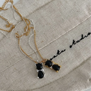 Collier chat en argent S925 avec pendentif agate noire et nœud en zircon sur lin beige
