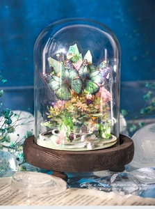 Detail of a 3D crystal butterfly in a glass dome display with a rustic wood base