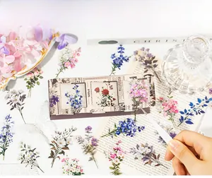 Gros plan d'autocollants PET de fleurs vintage appliqués avec une pince sur un journal