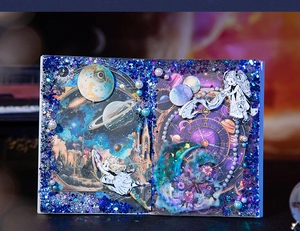 Detail of starry night theme junk journal with moon phases and glittering girl stickers