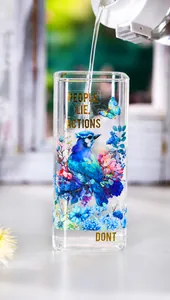 Detail of artistic rectangle glass cup with blue bird floral print and gold text