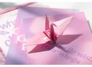Macro detail of paper crane with butterfly art card in purple pink gradient tones