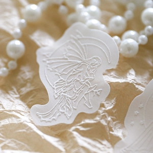Witte reliëfsticker met fee op maan op getextureerd papier met parels decoratie voor hobby