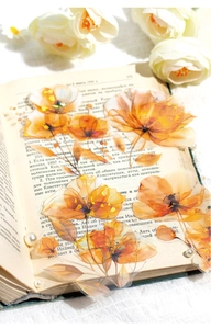 Close-up of orange watercolor PET stickers with gold foil on vintage book pages
