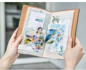 Detail of vintage watercolor PET stickers with travel motifs applied on a leather journal