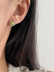 Close-up of cat-shaped silver earring with yellow zircon and pavé crystals on ear