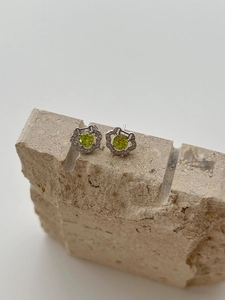 Detail of 925 sterling silver earrings with green gemstone and small diamond halo