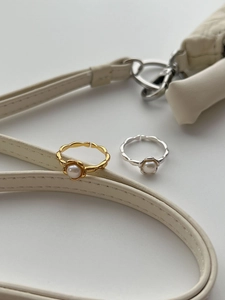 Close-up of irregular wave textured silver and gold rings with white freshwater pearls