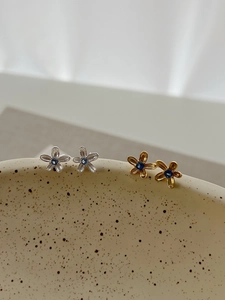 Détail de boucles d'oreilles fleurs en argent et or avec zircons bleus centraux