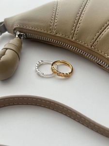 Detailed close-up of chain-style rings in gold and silver with pave micro diamonds