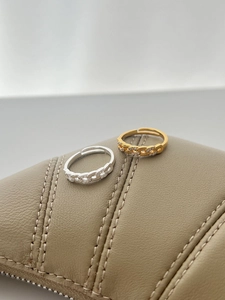 Detail of gold and silver chain rings with sparkling zircon inlay on leather background