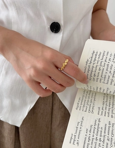 Detail of gold irregular textured ring worn by hand in a minimalist lifestyle setting
