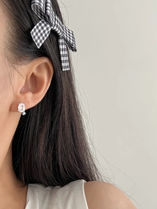 Close-up of a 925 sterling silver earring with light blue crystal on earlobe