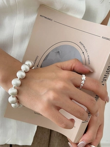 Close-up of 925 sterling silver lava texture ring and beaded bracelet on a hand