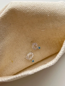 Close-up of S925 silver stud earrings with oval topaz and round blue gemstone inlay