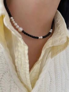 Close-up of a 925 silver black onyx and gradient pearl necklace on a model neck