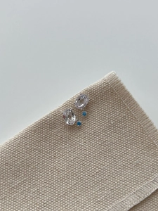 Close-up of 925 silver stud earrings with oval clear crystal and blue topaz accents