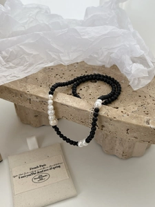 Close-up of black onyx beads and baroque freshwater pearls on a silver lobster clasp chain