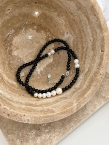 Detail of black onyx and gradient white pearl necklace in a stone bowl