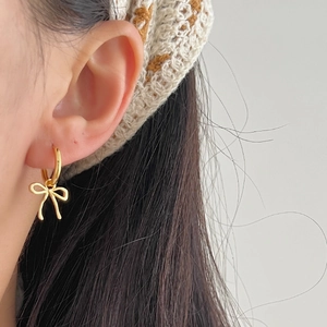 Minimalist 925 sterling silver bow earrings in gold finish worn on ear closeup