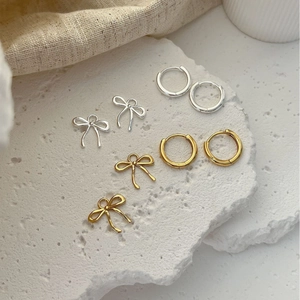 925 Sterling Silver bow stud earrings and minimalist hoop set on a stone tray