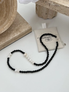 Detail of 925 silver black onyx and baroque pearl necklace with heart charm