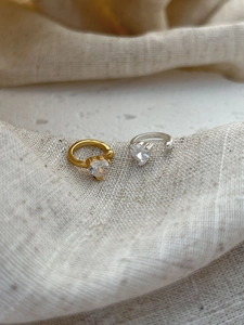 Close-up of gold and silver heart-shaped ear cuffs with sparkling clear cubic zirconia