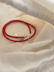 Gros plan du fermoir en argent S925 et des perles de corail rouge sur le collier d'été