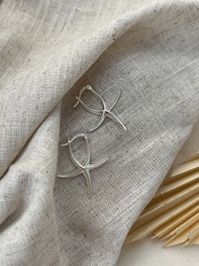 Macro shot of polished S925 sterling silver starfish earrings on a linen texture background