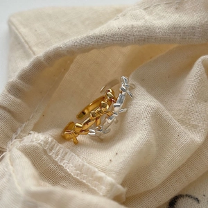 Elegant gold and silver S925 sterling silver bow open rings on a cream fabric pouch