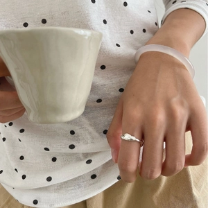 Minimalist silver wavy ring and translucent bangle styled with a neutral casual outfit